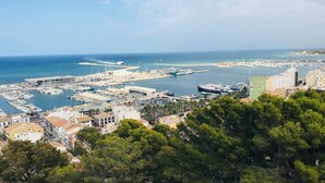 Un puerto deportivo costero con barcos, un edificio grande con fachada blanca y un cielo azul despejado.
