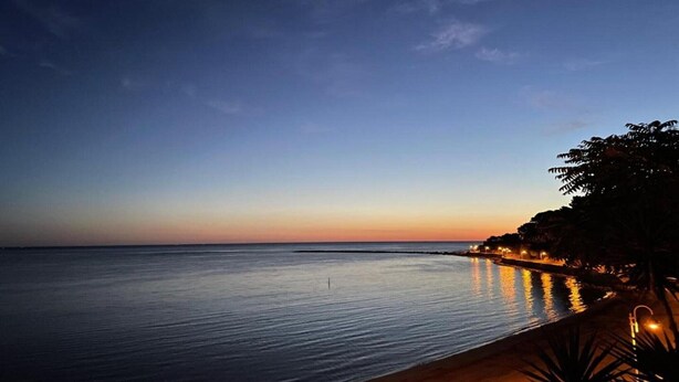 Una vista tranquila del mar al atardecer, con un horizonte despejado y una costa lejana.