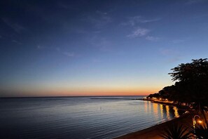 Une vue paisible sur la mer au crépuscule, avec un horizon dégagé et une côte lointaine.