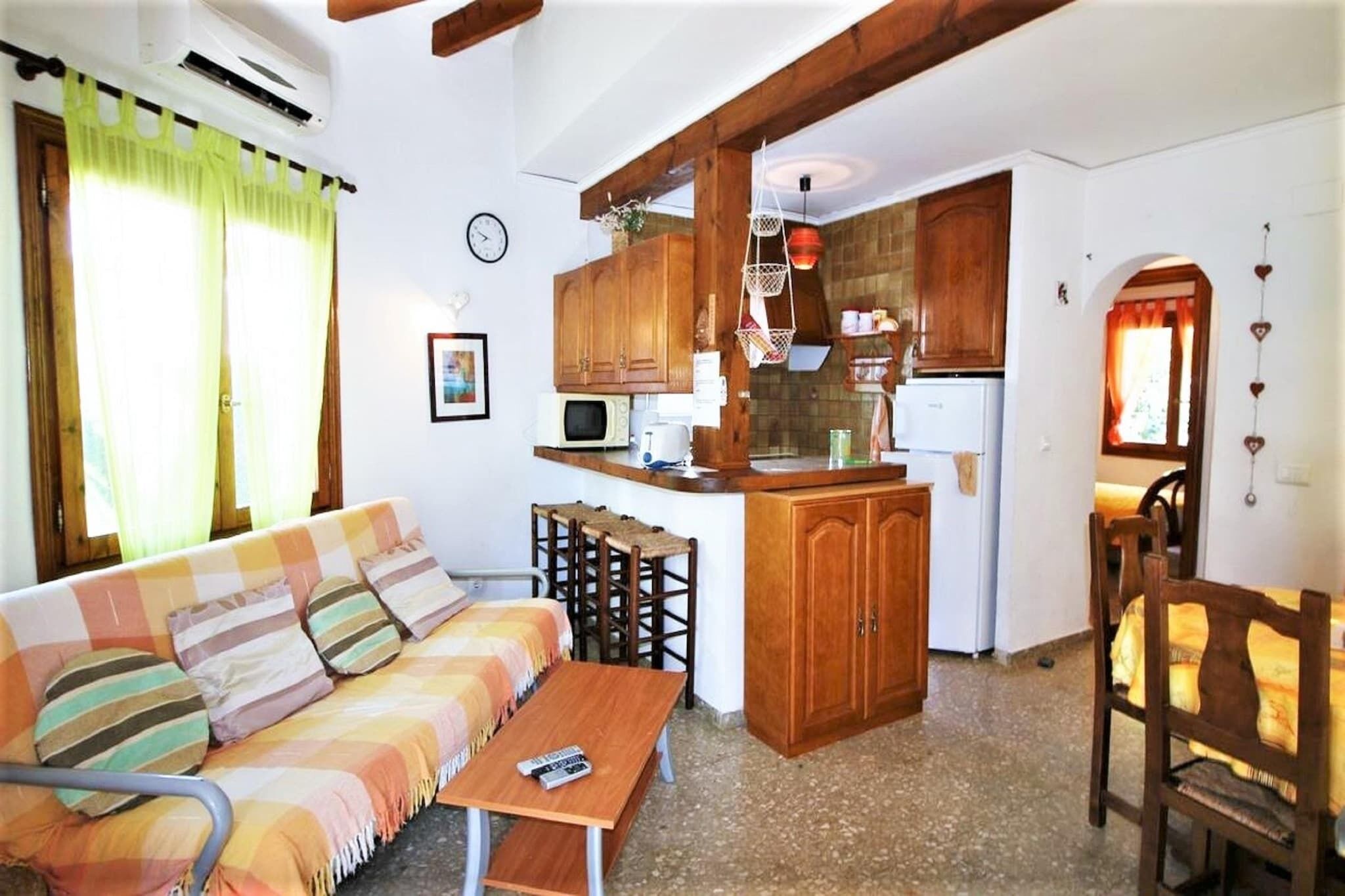 Een ruimtelijk ingerichte leefruimte met een bank, een tafeltje, een kitchenette en een eethoek.