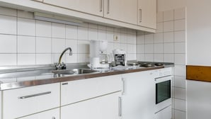 Une cuisine moderne avec des meubles blancs, un évier en acier inoxydable, une machine à café et un four.
