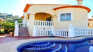A building with a pool, a balcony, and a staircase leading to the entrance.