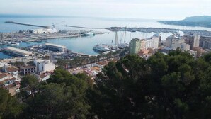 A coastal cityscape with a marina, a bridge, and a mix of residential and commercial buildings.