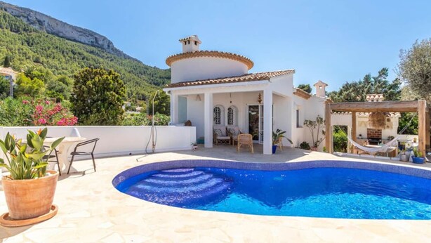 A white villa with a swimming pool, a patio with outdoor furniture, and a mountain backdrop. - Scenic Villa, Costa Blanca (Denia)