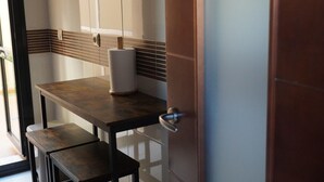 A bathroom with a wooden table, a towel dispenser, and a door with a silver handle.