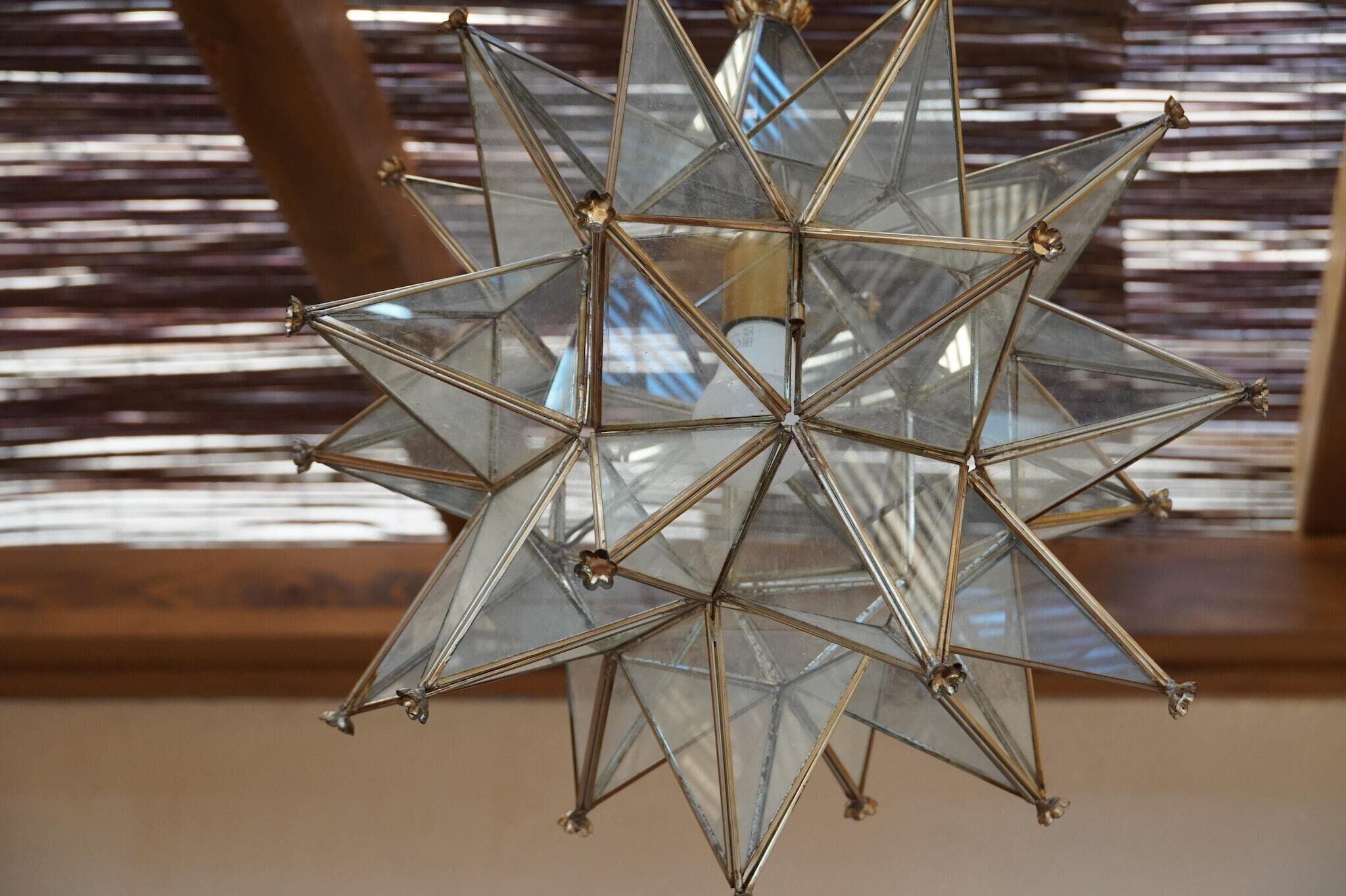 Una lámpara colgante de diseño geométrico con múltiples paneles de vidrio y varillas de metal, suspendida del techo.
