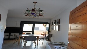 A dining area with a star-shaped chandelier, a wooden door, and a view through a glass door.