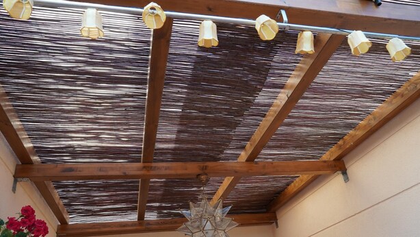 A wooden ceiling structure with a star-shaped hanging light fixture and a series of cylindrical lights.