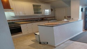 Een keuken met witte kastjes, een granieten aanrechtblad en een klein eiland.