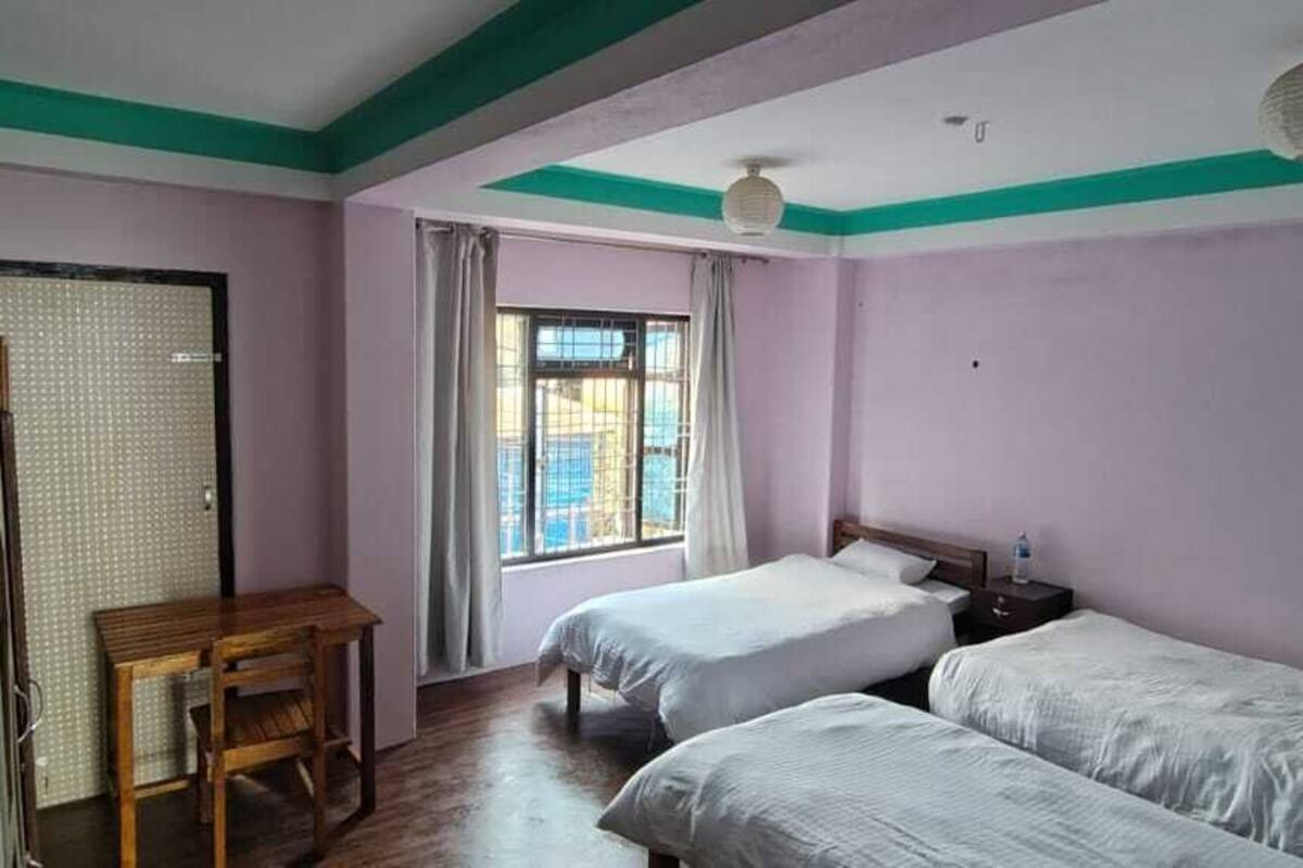 Habitación con dos camas, un escritorio y ventana con cortinas.