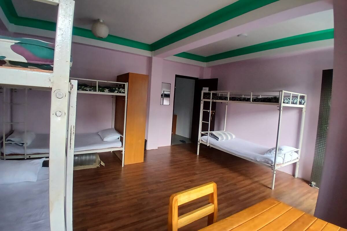 Un dormitorio con literas, una mesa de madera y una silla.