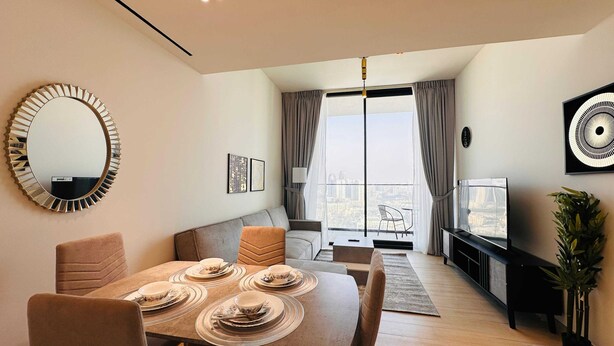 A modern living room with a dining area, a large mirror, and a TV.