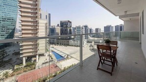 A balcony with a view of a cityscape, including modern buildings and a sports field.
