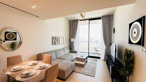 A modern living room with a sofa, dining table set, and a TV.