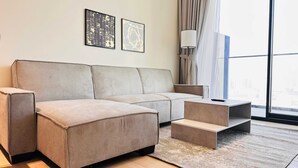 A modern living room with a sectional sofa, a coffee table, and a small side table. There are two framed artworks on the wall and a floor lamp.