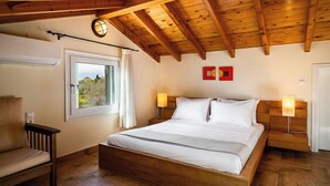 A bedroom with a wooden ceiling, a bed with white bedding, two bedside lamps, a window with a view, and a chair.
