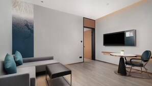 Ein modernes Wohnzimmer mit einem grauen Sofa, einem kleinen Tisch und einem an der Wand befestigten Fernseher.