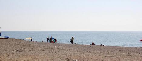 A beach with people, umbrellas, and a wooden boardwalk.