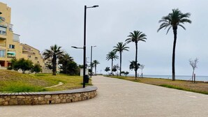 A paved walkway lined with palm trees and a stone wall, leading to a beach. - Apartment in Salobreña with Sea Views (Salobreña)