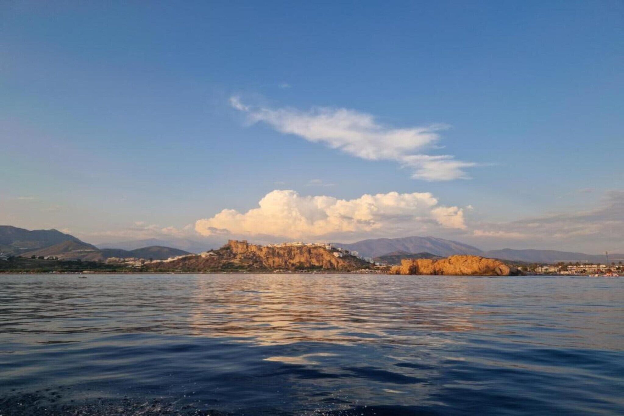 Un lac paisible avec une petite île au centre, entouré de montagnes.