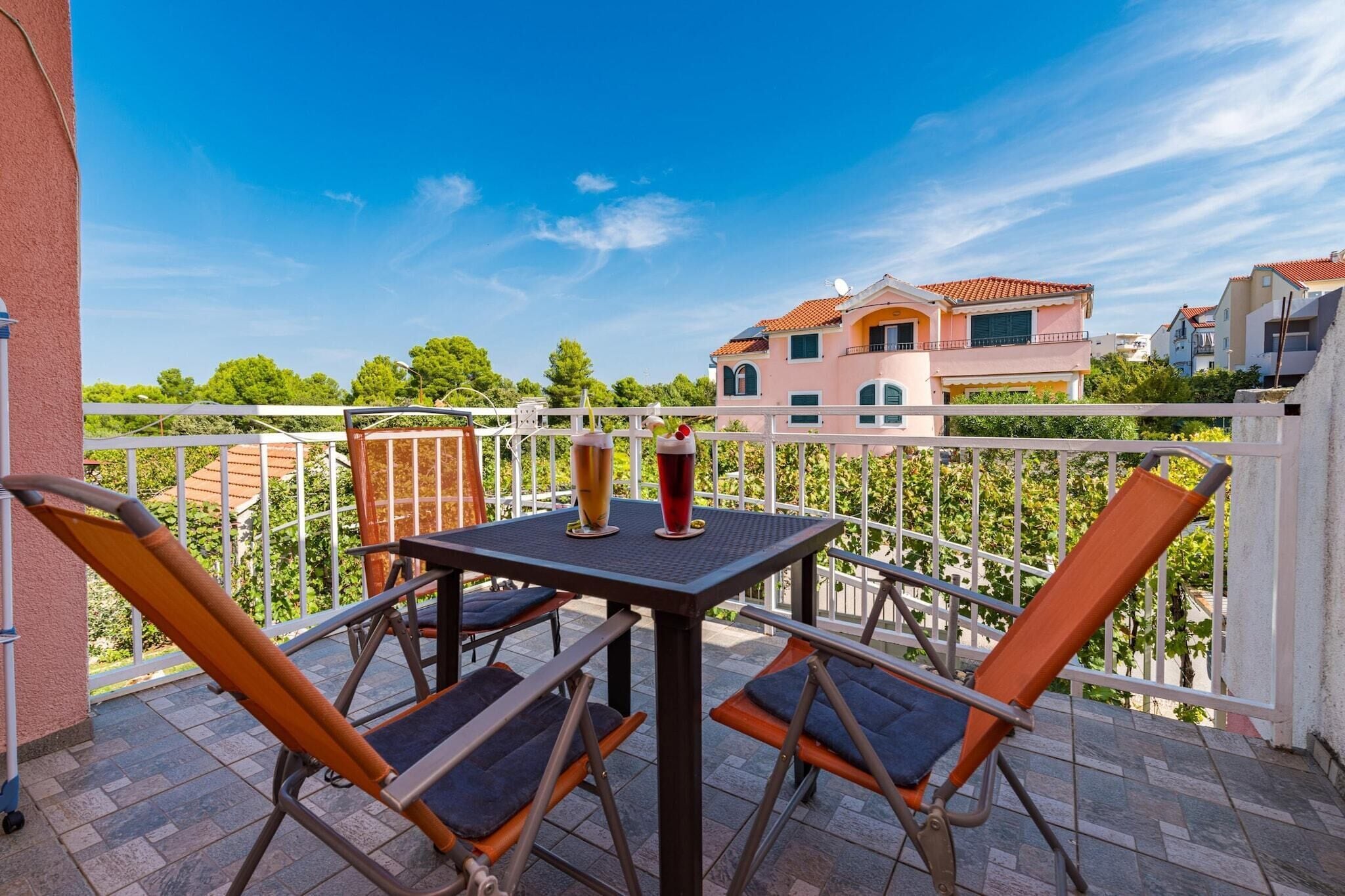 Un balcón con mesa y sillas, con vistas a una zona residencial con casas y árboles.