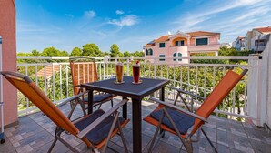 A balcony with a table and chairs, overlooking a residential area with houses and trees. - Apartment Šibenik near Beach Gaj (Šibenik-Brodarica)