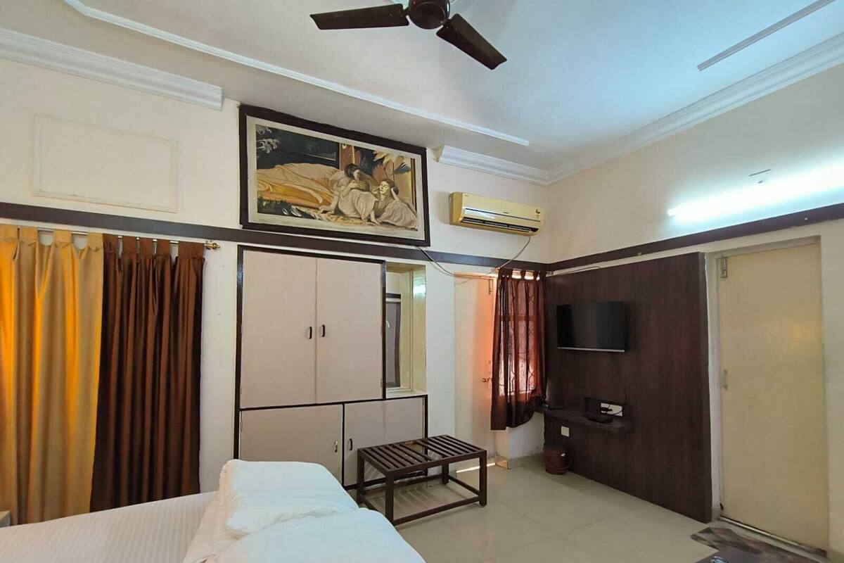 Quarto de hotel com cama, armário, televisão e ventoinha no teto.