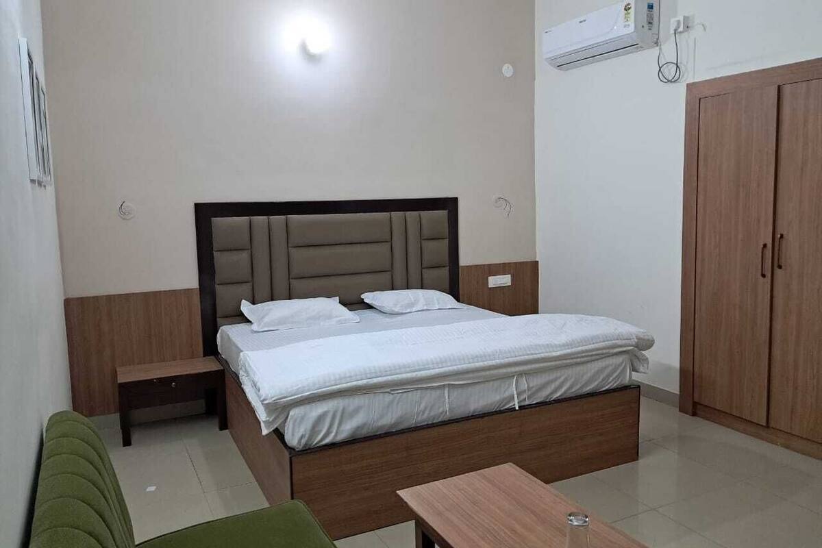 Quarto com cama, mesas de cabeceira, guarda-roupa e uma pequena mesa.