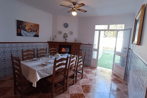 A dining room with a table set for four, a fireplace, and a view of the outdoors.