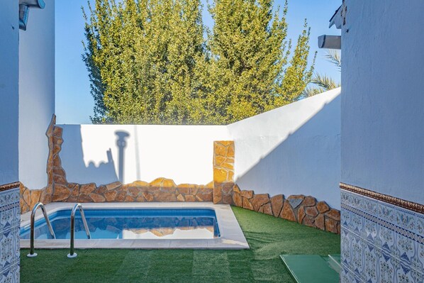 A swimming pool with a stone wall and a tree in the background.