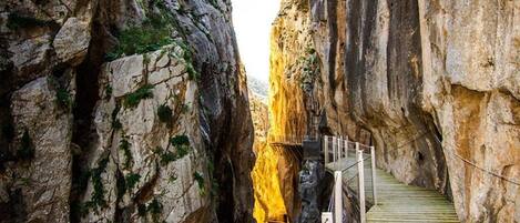 Eine schmale, felsige Schlucht mit einer Holztreppe, die hinabführt.