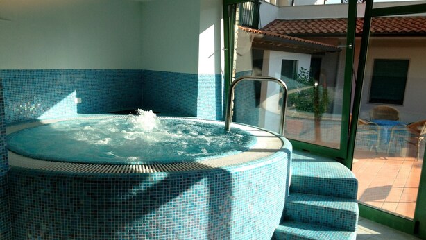 Un jacuzzi con revestimiento de azulejos, una escalera metálica y escalones que lo conducen.