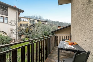 Enjoy a meal on the balcony overlooking a serene garden and residential area.