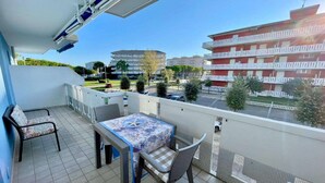 A balcony with a table and chairs, a view of a red building, and a clear sky. - Apartment in Porto Santa Margherita near Beach (Porto Santa Margherita (VE))