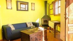 A room with a yellow wall, a blue sofa, a wooden coffee table, and a fireplace.
