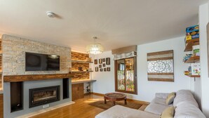 A modern living room with a fireplace, a sofa, and a dining area with a wooden table and chairs. - Holiday home in Córdoba with Swimming pool (Zambra)