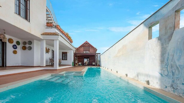 A swimming pool with a view of a building with a balcony and a red roof. - Holiday home in Córdoba with Swimming pool (Zambra)