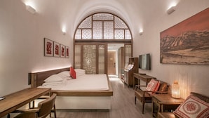 A hotel room with a bed, desk, chairs, a TV, and a painting on the wall. - WANDA REALM Yan'an (Yan'an)