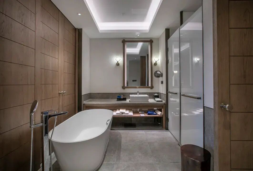 Un baño moderno con una bañera independiente, un tocador con espejo y zona de ducha.