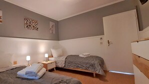 Ein Schlafzimmer mit zwei Betten, Nachttischen mit Lampen und Bildern an den Wänden.