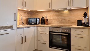 Eine moderne Küche mit weißen Schränken, Edelstahlgeräten und einer Holzrückwand.