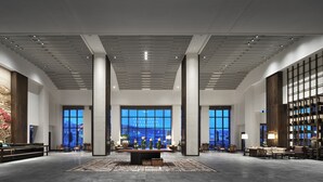 A spacious lobby with a central reception desk, seating areas, large windows, and a modern ceiling design. - WANDA JIN Yan'an (Yan'an)