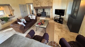 Una sala de estar acogedora con chimenea de piedra, un sofá, una mesa de centro y un televisor.