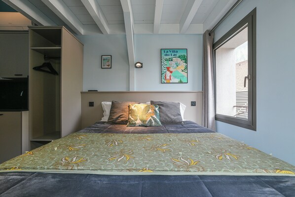 Un dormitorio con cama, armario, un póster en la pared y ventana.
