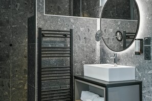 Un baño moderno con un lavamanos rectangular, un perchero, un espejo y un altavoz integrado en la pared.