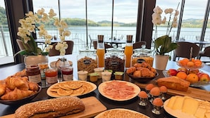 A breakfast buffet with pastries, bread, eggs, and fruits by a lake view. - La Villa du Lac (Aiguebelette-le-Lac)