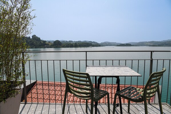 A balcony with a table and two chairs overlooking a lake with boats and hills in the background. - La Villa du Lac (Aiguebelette-le-Lac)