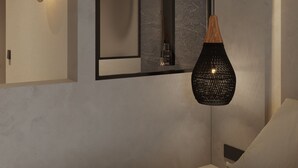 A modern bedroom with a large mirror, a hanging light fixture, and a built-in shower. - néreya luxury rooms (Rhodes)