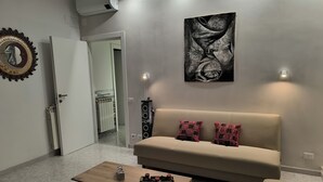 A modern living room with a beige sofa, a wooden coffee table, and a large abstract painting on the wall.