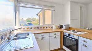 A kitchen with a double sink, a microwave, an oven, and a window with a view of the outside. - Host Stay Park View (Thetford)